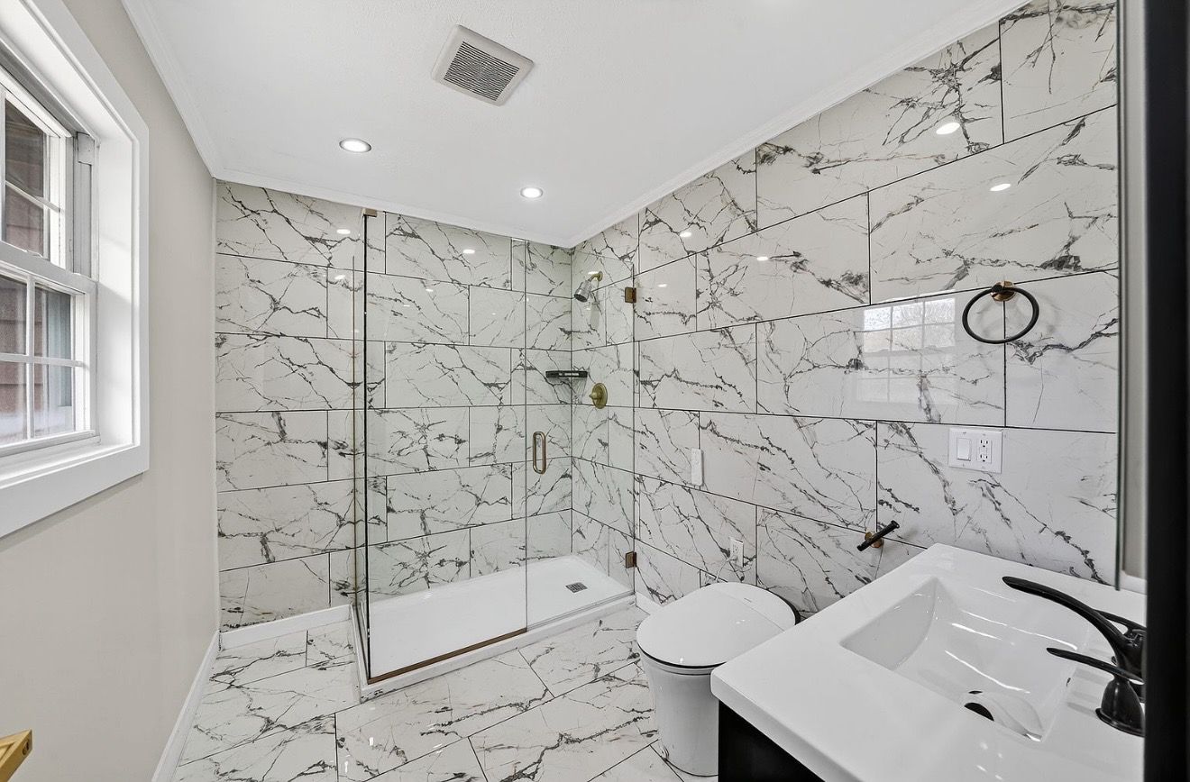 Completed bathroom remodel with marble-look tile and glass shower